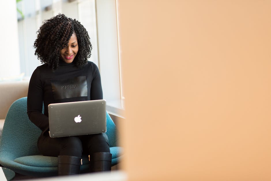 African American woman happily working on a laptop in a modern office setting