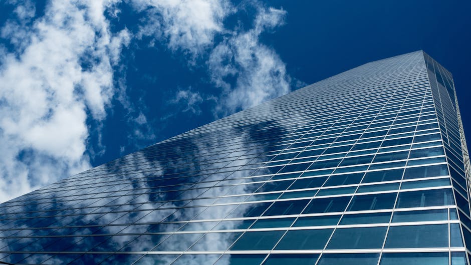 Low-angle view of a modern skyscraper with reflective glass windows against a blue sky